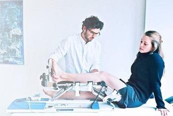 Vrouw op onderzoekstafel met haar knie in een CPM toestel